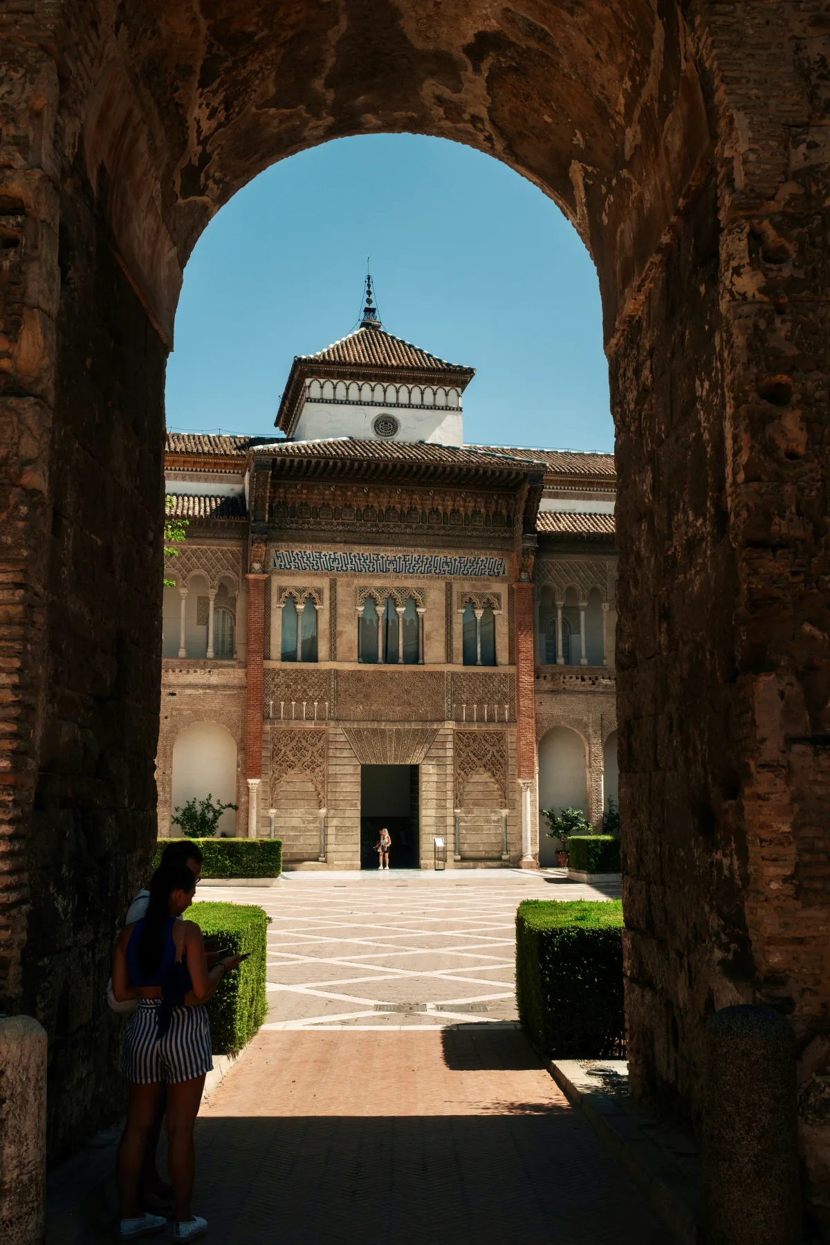 Palace of King Pedro in the Real Alcázar of Seville framed by a dark archway