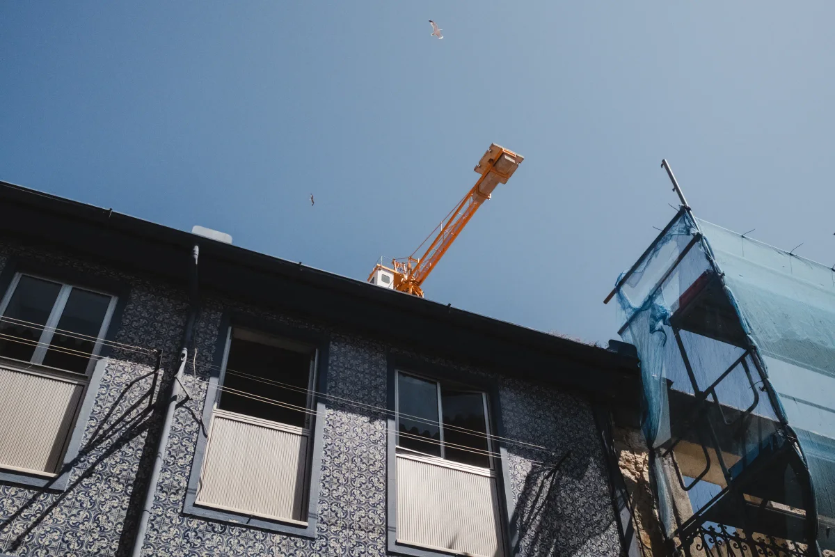 Blue azulejo-tiled building facade with an orange construction crane in the sky