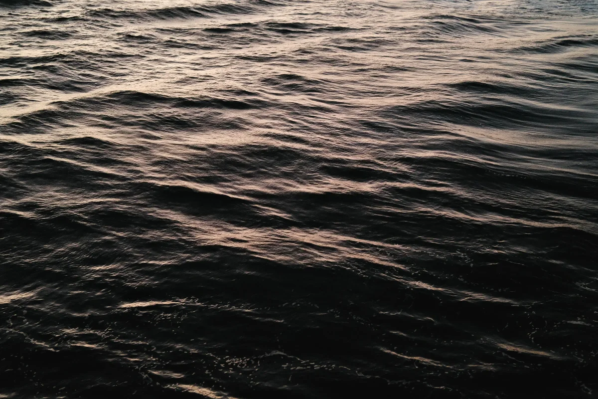 Dark rippling water catching faint pink light at dusk