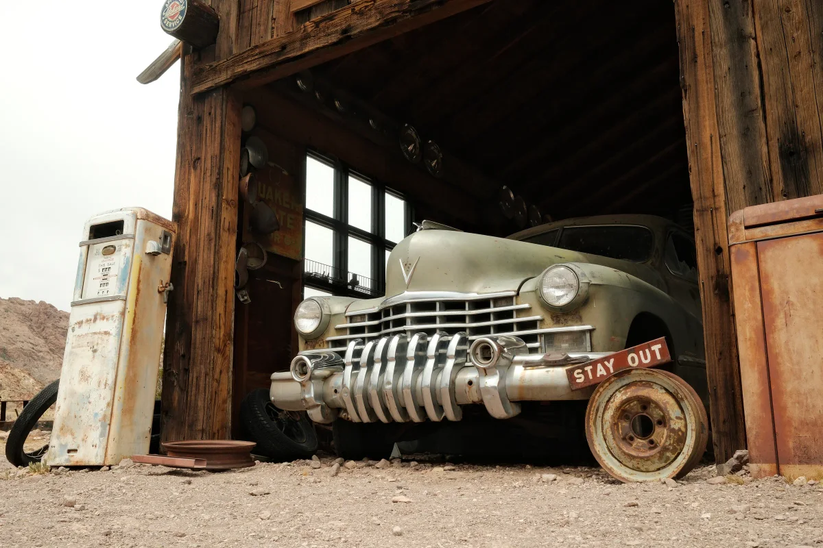 Vintage Cadillac in a wooden garage beside an old gas pump at Nelson Ghost Town, Nevada
