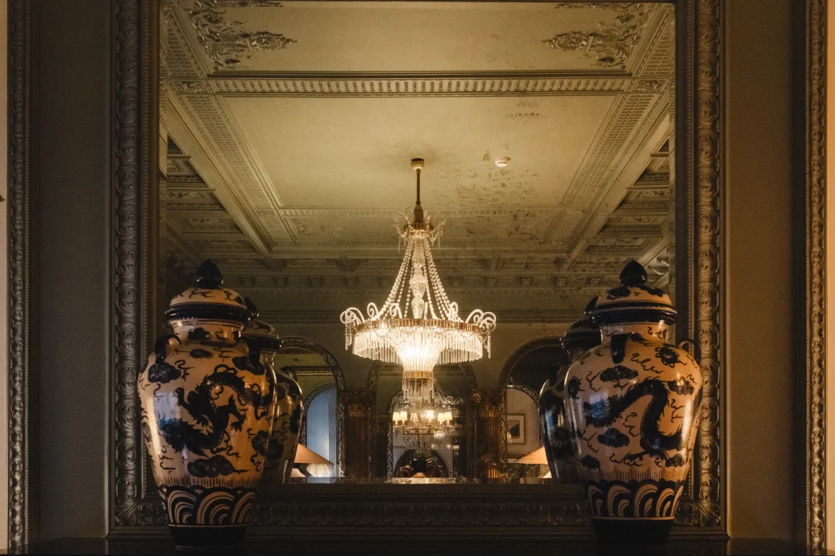 Pair of blue-and-white dragon vases before a mirror reflecting a crystal chandelier