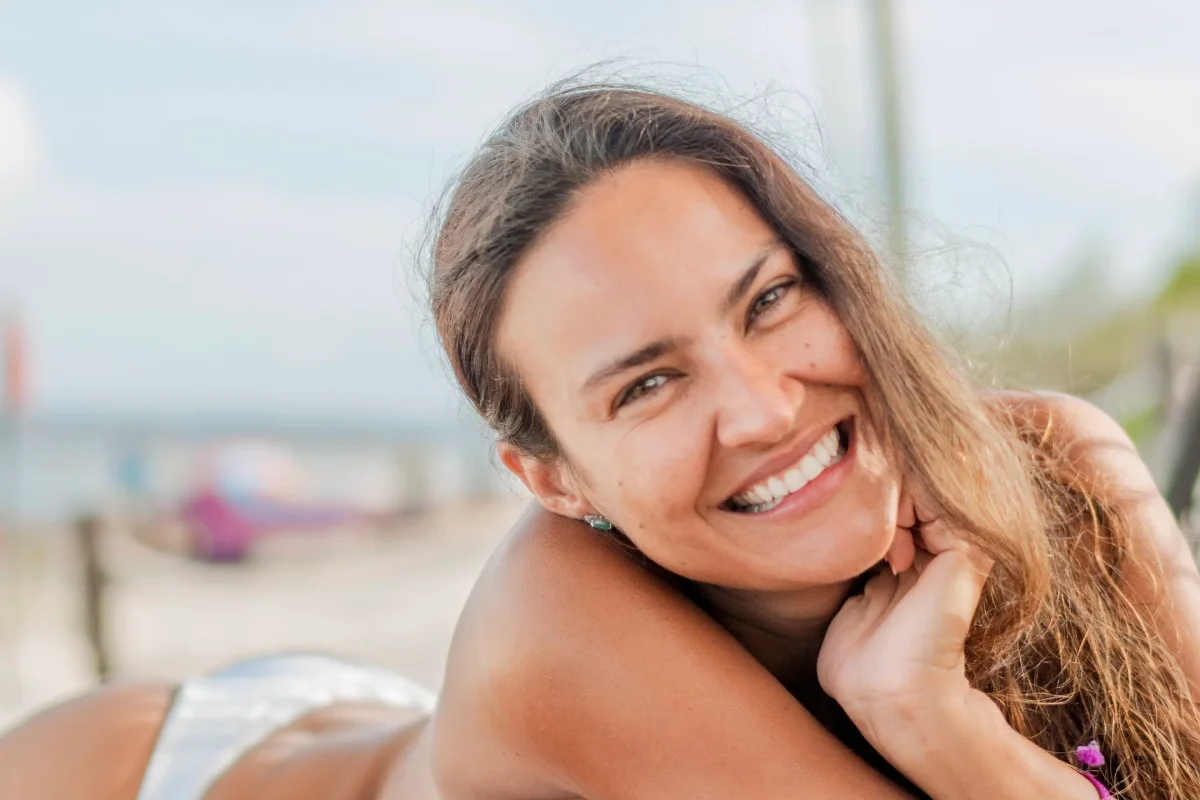 Close-up portrait of a laughing woman resting her chin on her hand at the beach