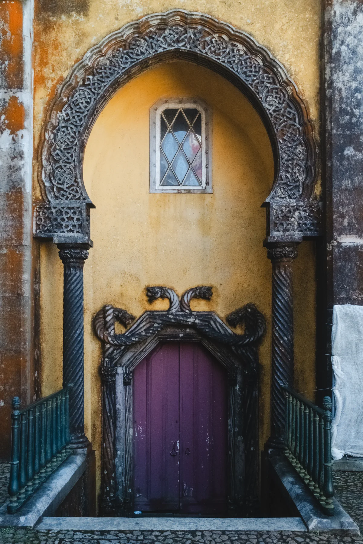 Ornate carved stone archway around a purple door on an ochre wall