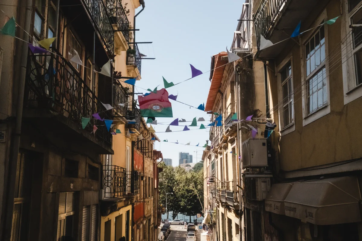 Colorful triangular bunting and a Portuguese flag strung across a narrow street