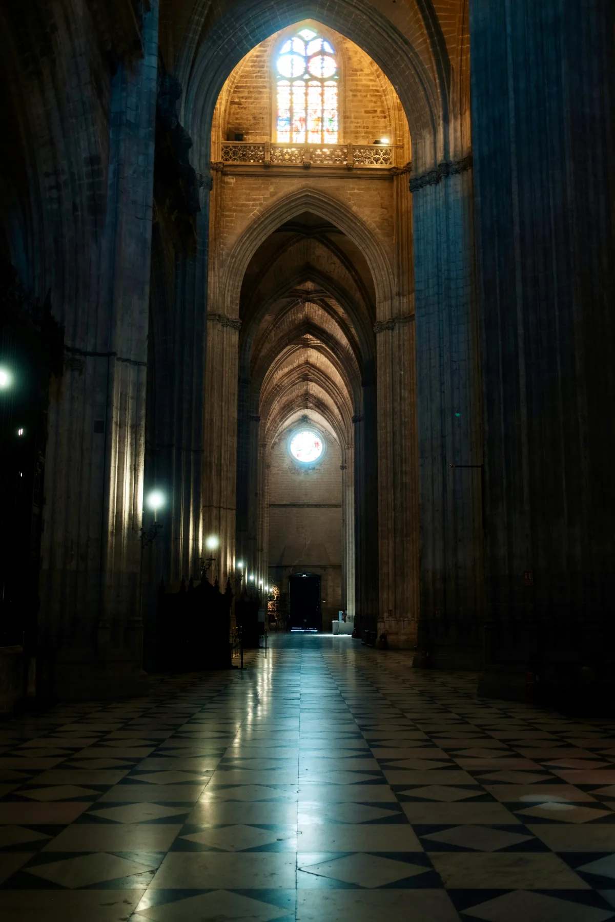 Gothic cathedral nave with tall pillars and a gleaming checkered marble floor