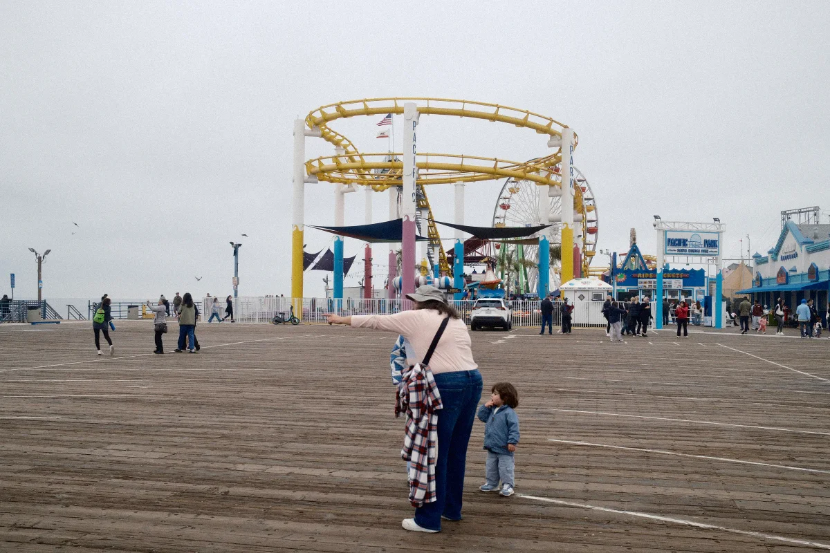 Mother pointing across the Santa Monica Pier deck as a toddler looks on