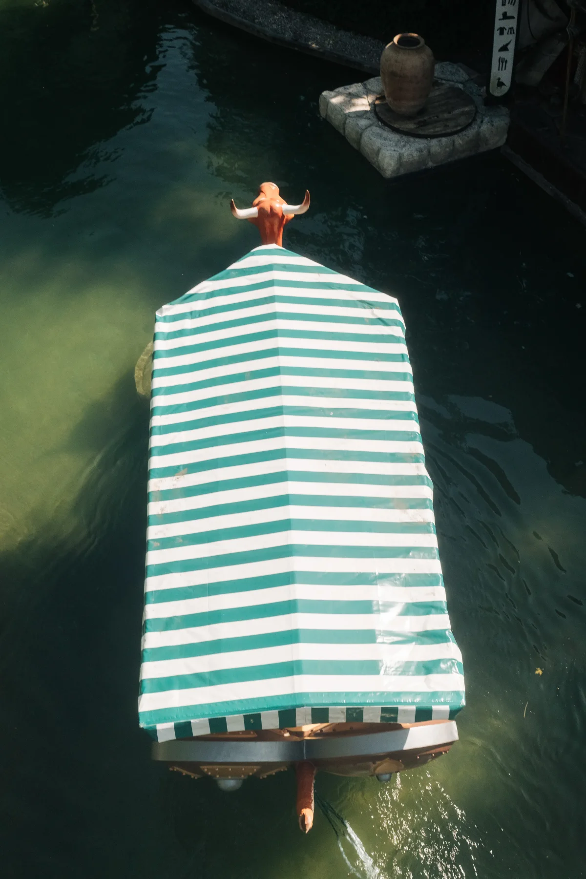 Boat with a green-and-white striped canopy seen from above on dark water