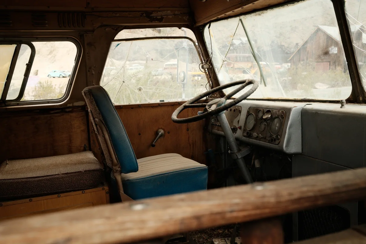 Cab of an abandoned old truck with a blue seat and large steering wheel at Nelson Ghost Town