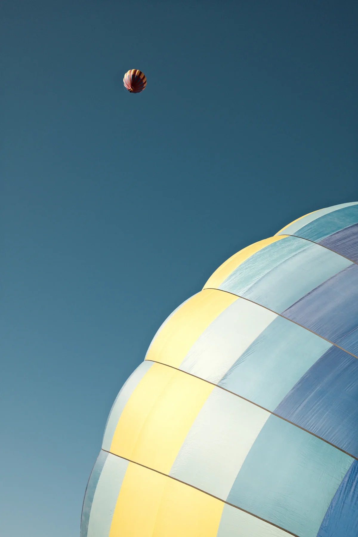 Pastel hot air balloon envelope with a tiny balloon high above at the Mesquite, Nevada balloon festival
