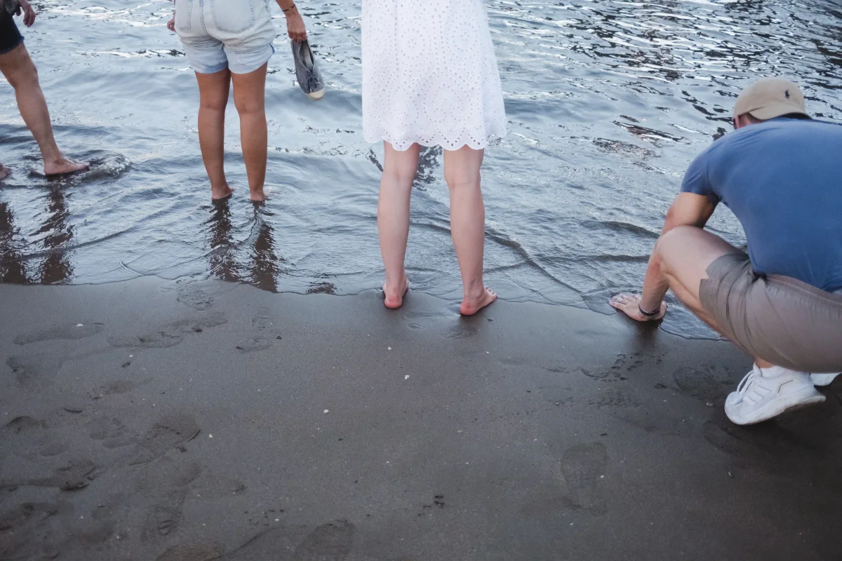 Bare feet stepping into the river at the water's edge, a woman holding her shoes