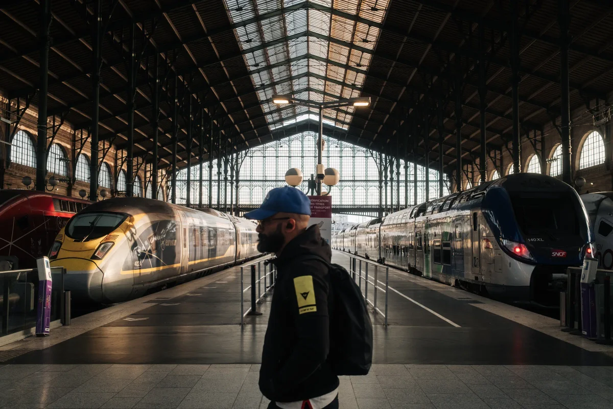 Man in a blue cap on a platform under the iron and glass shed of Gare du Nord