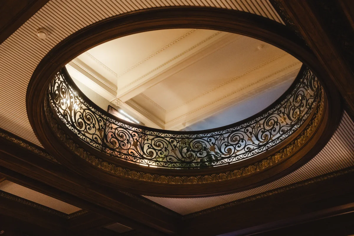 Looking up through an oval ceiling opening ringed with an ornate wrought-iron railing