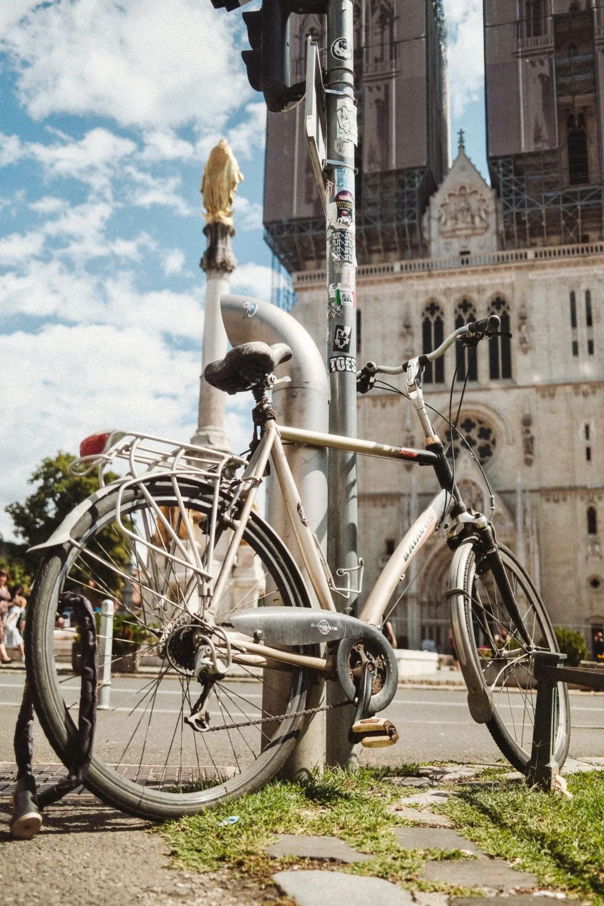 Bicycle locked to a pole in front of Zagreb Cathedral and a golden Virgin Mary statue