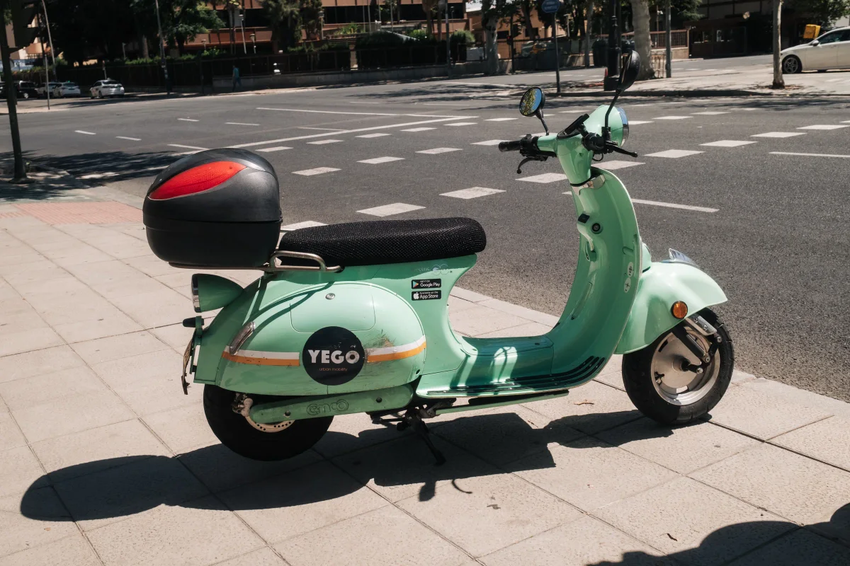 Mint green rental scooter parked on a sunny city sidewalk