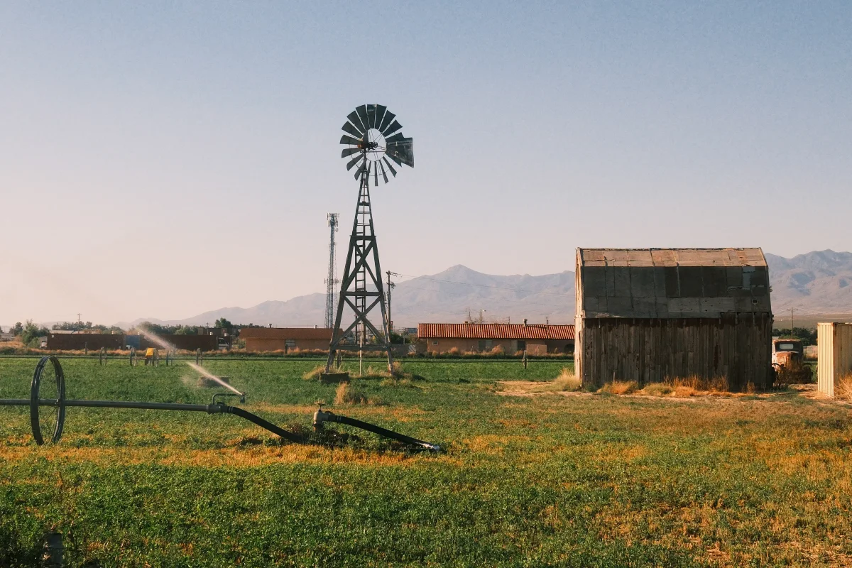 Old windmill and wooden barn in a green field with desert mountains behind