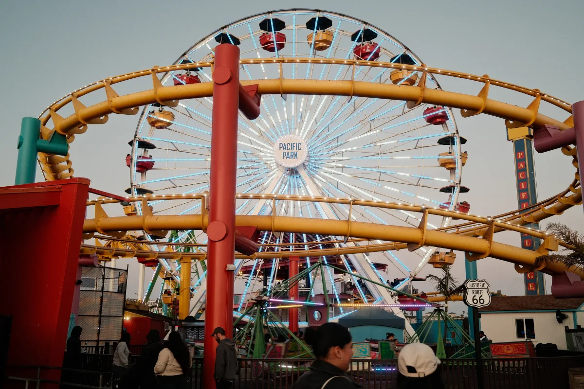 Santa Monica Pier Ferris wheel and roller coaster at dusk with a Route 66 sign