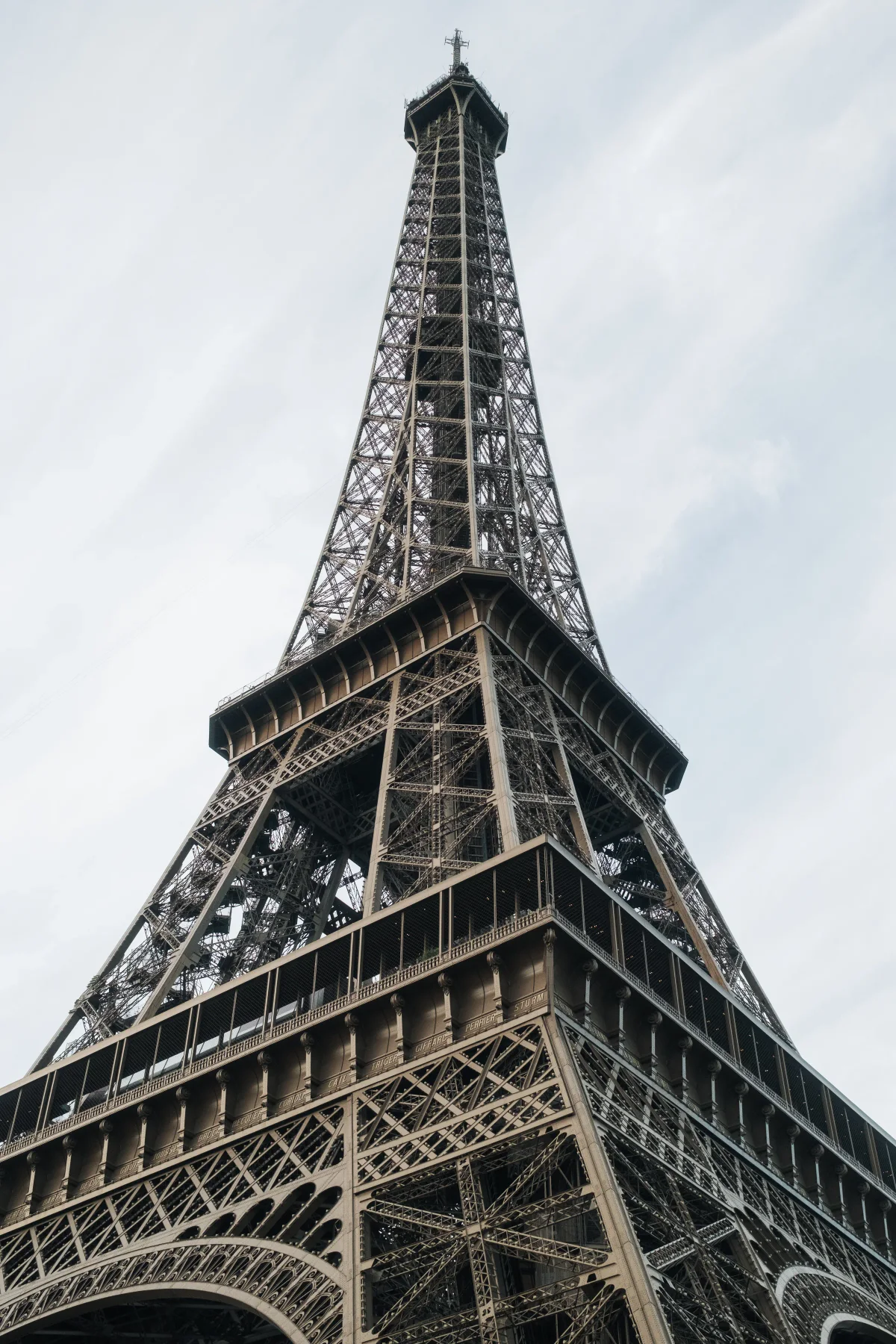 Eiffel Tower seen from directly below against a pale sky