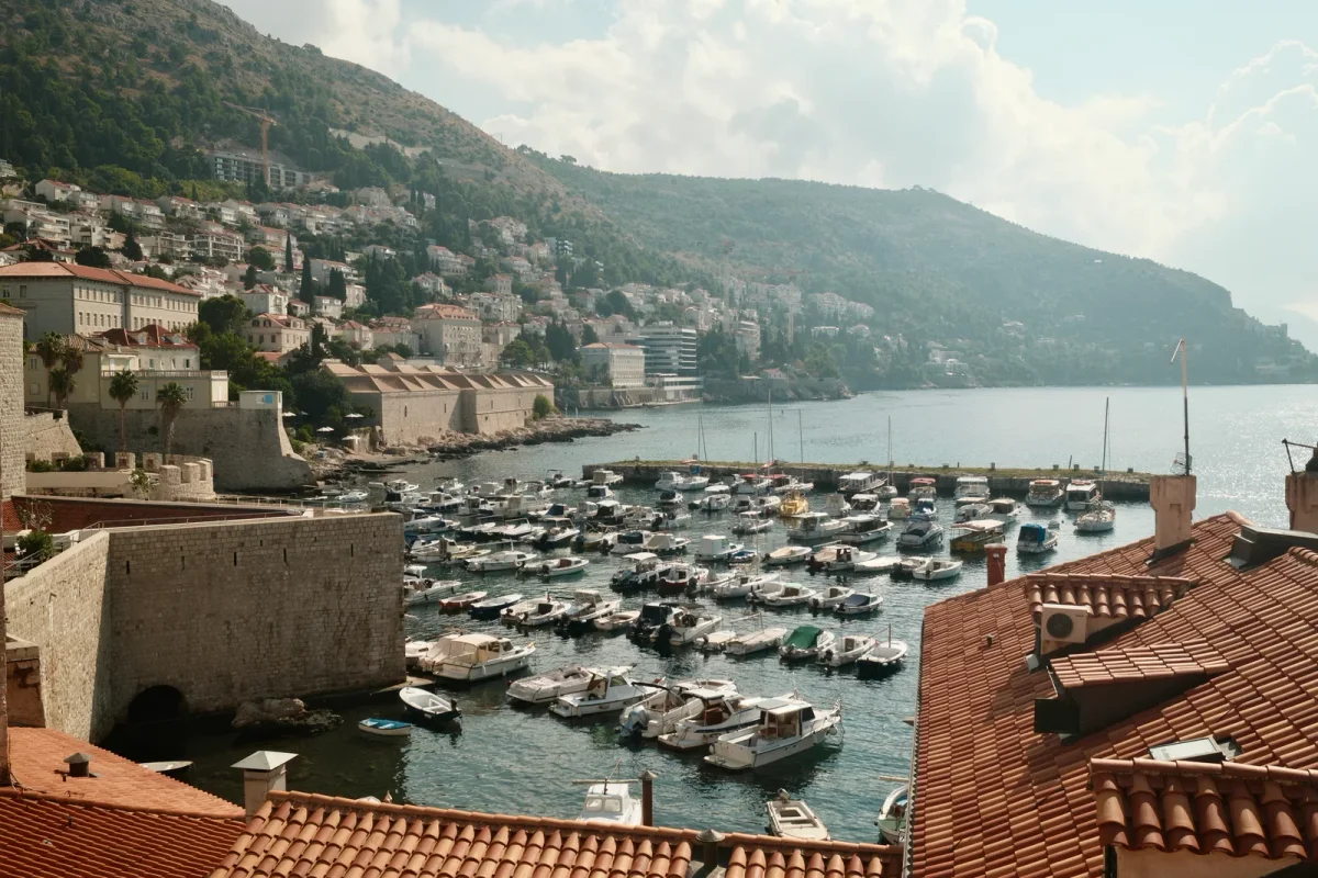 Coastal marina and hillside town beneath mountains across the bay
