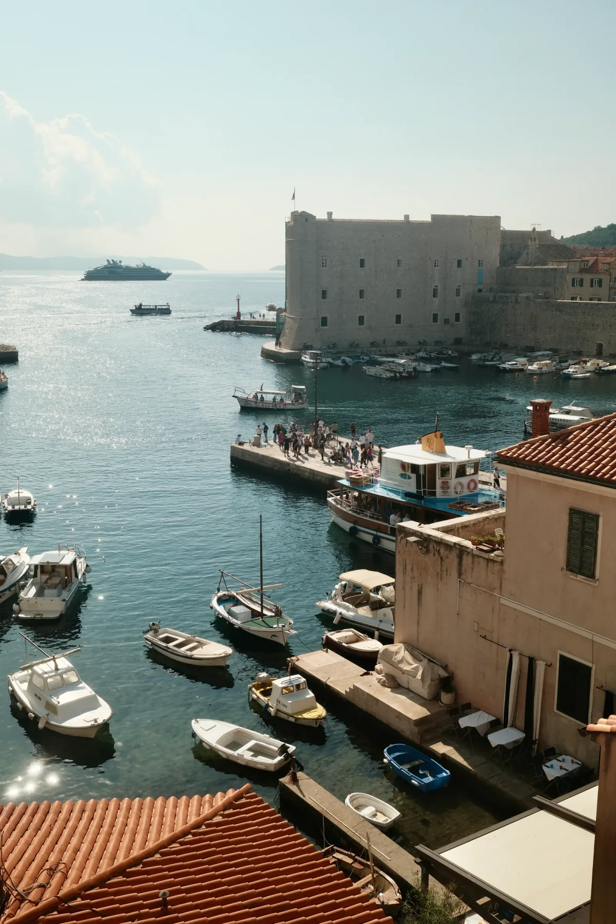 Old coastal harbor and small boats viewed from terracotta rooftops