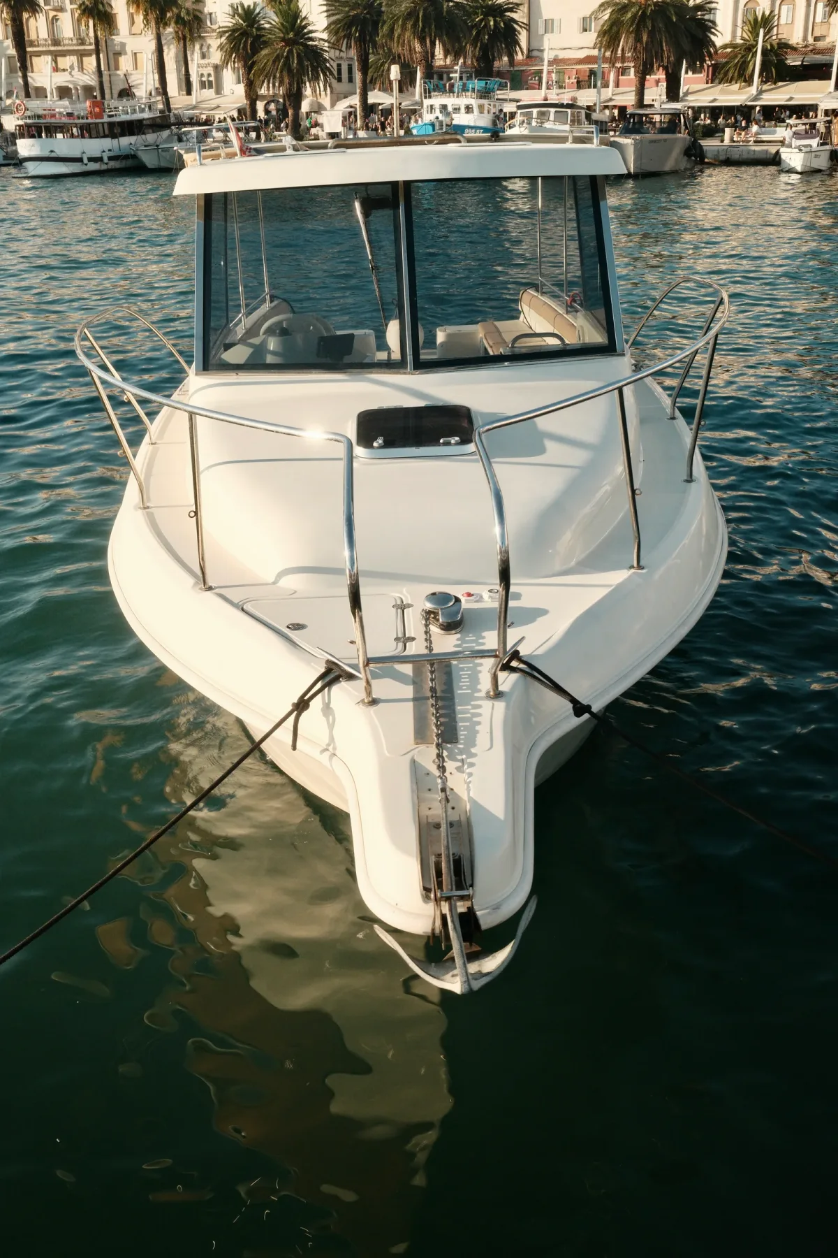 White cabin motorboat seen head-on at a marina mooring
