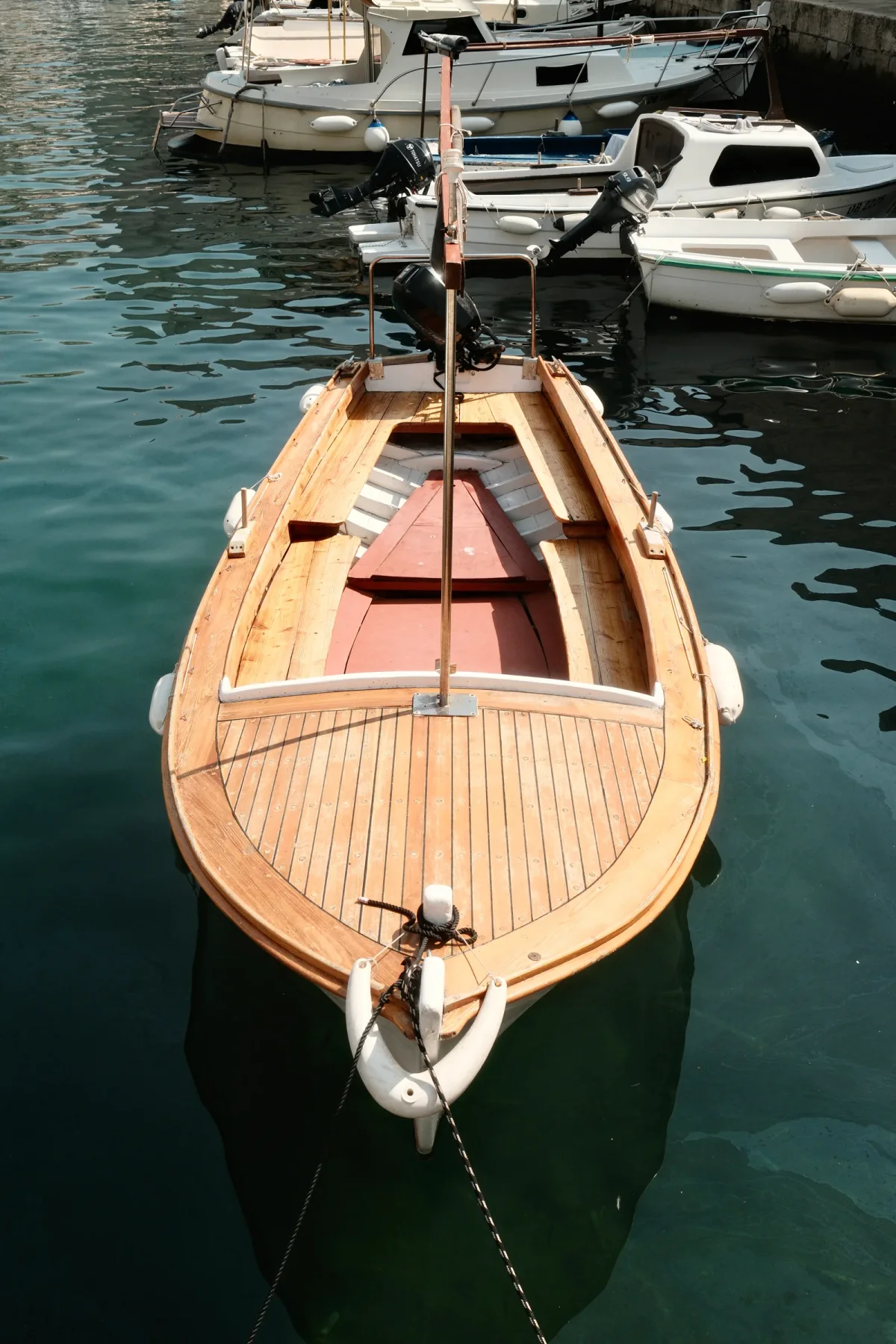 Varnished wooden launch seen from above at its harbor mooring