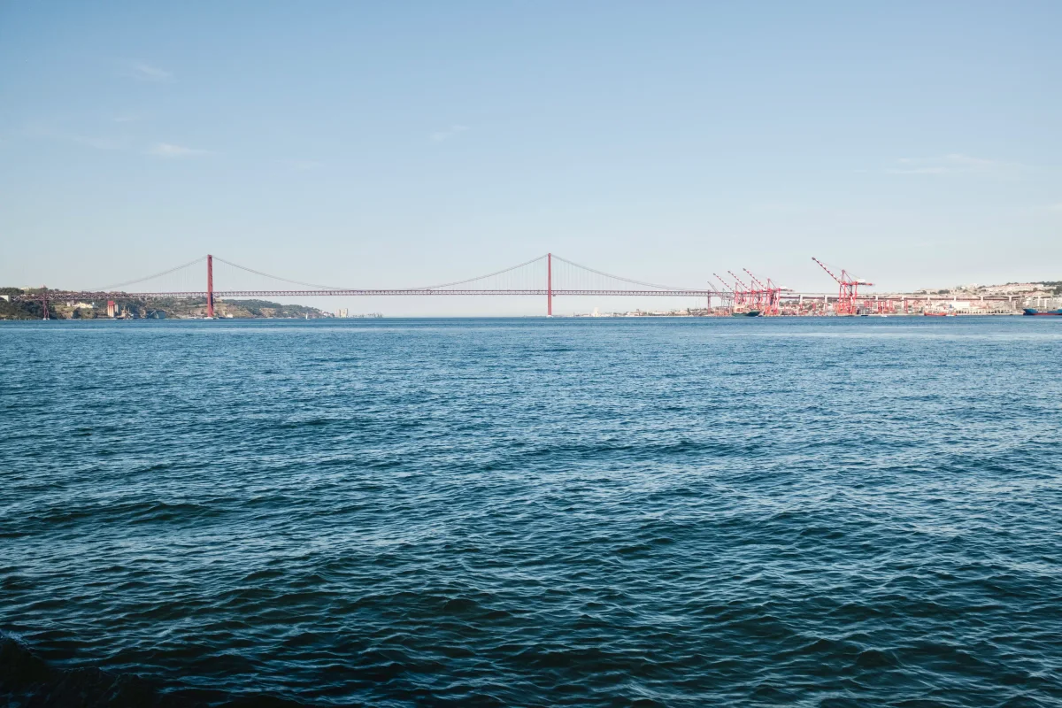 The red 25 de Abril suspension bridge spanning the Tagus River beneath a clear blue sky