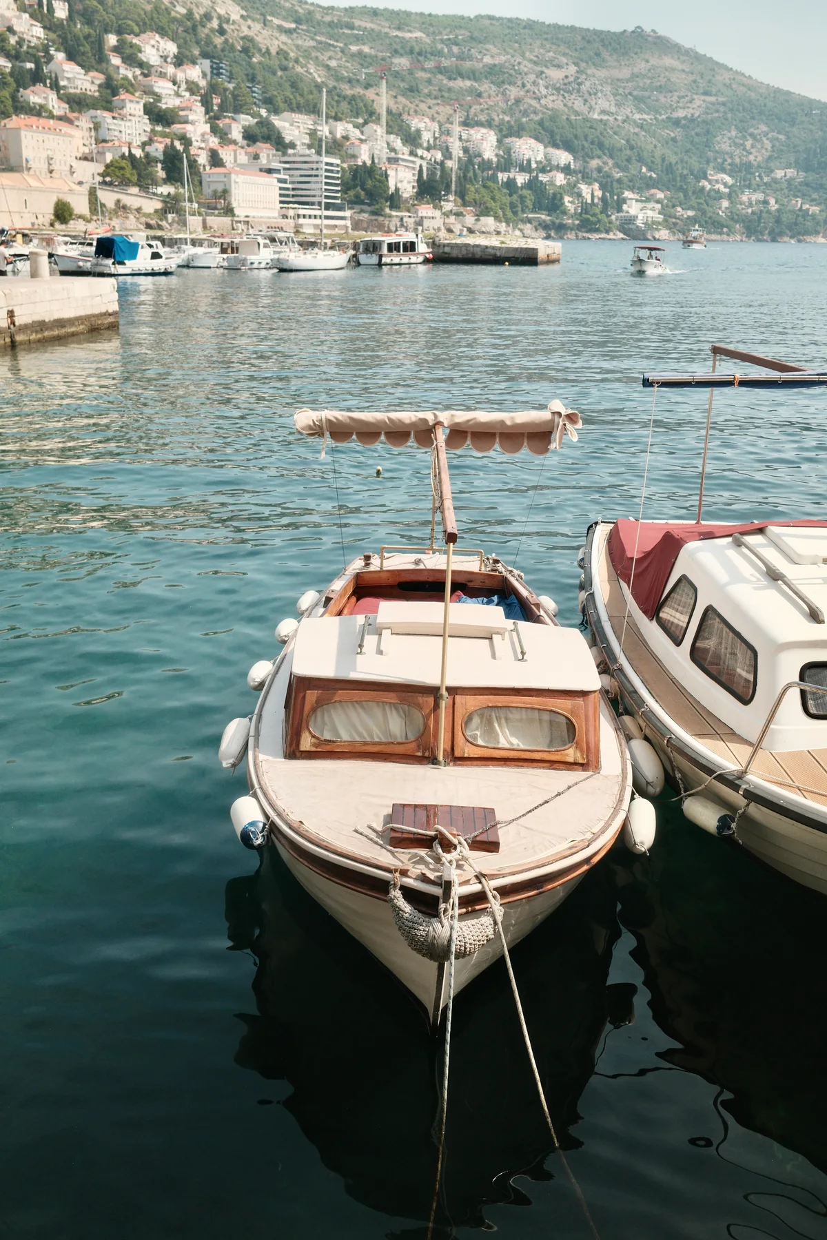 Wooden motor launch moored among boats beneath a densely built hillside town